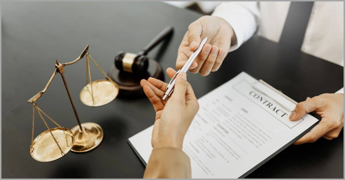 Hands exchanging pen with legal contract and justice scale on desk